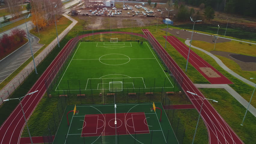 Large football field with green turf on modern sports ground aerial view. Urban court for team ball games training