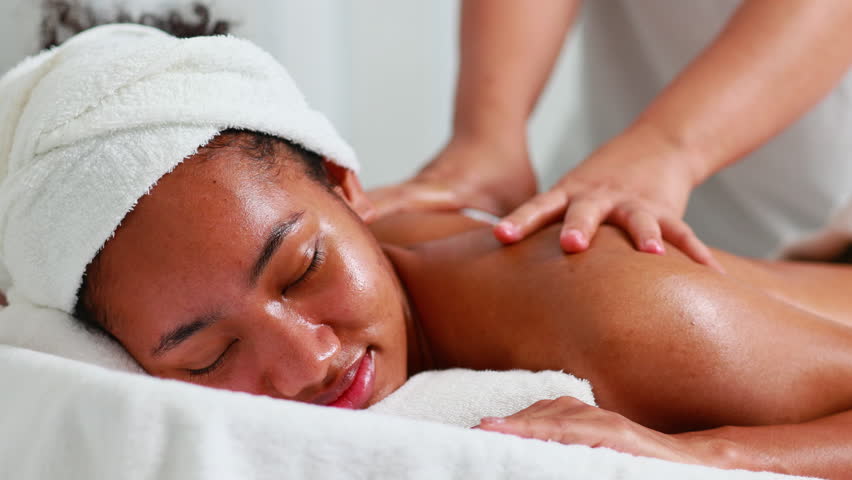 Back spa massage. Beautiful African American woman getting massage in beauty spa and wellness center. Facial treatment and skin care concept. Royalty-Free Stock Footage #1099073301