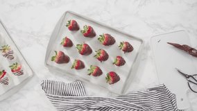 Time lapse. Flat lay. Step by step. Drizzling melted chocolate from pastry piping bag to chocolate covered strawberries.