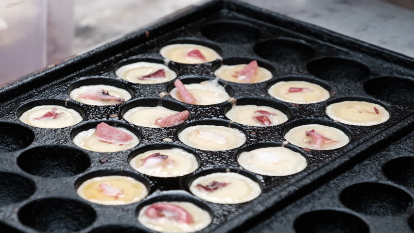 Close up shot of making Takoyaki on hot pan with hands in the street food area