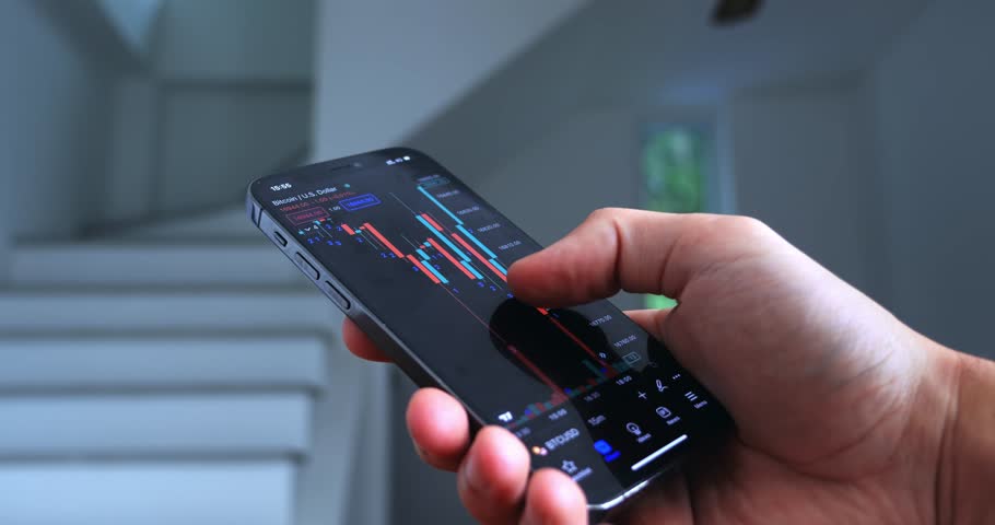 Close up trader investor broker using mobile phone app analyzing financial data stock market price on mobile phone, checking online trading platform application, buying cryptocurrency on home interior Royalty-Free Stock Footage #1099078927