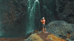 Active lifestyle people travel in tropical rainforest jungle and enjoy beautiful waterfall hidden in tropical rainforest jungle on nature background 4K Aerial view