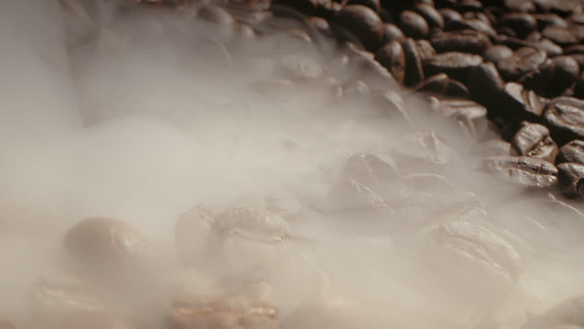 Aromatic coffee beans are roasted in frying pan,smoke comes from coffee beans. Soft diffuse smoke coming from roasted coffee beans.Macro shot coffee bean roasting smoke coming from bean roasting