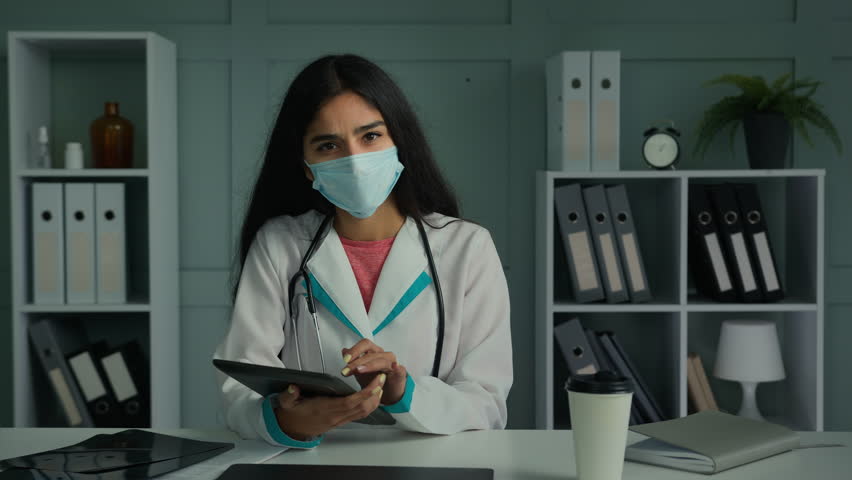 Web camera view young Arabian ethnicity woman doctor in face mask calling video chat virtual online consultation using healthcare app on digital tablet search web medical info modern tech telemedicine | Shutterstock HD Video #1099081311