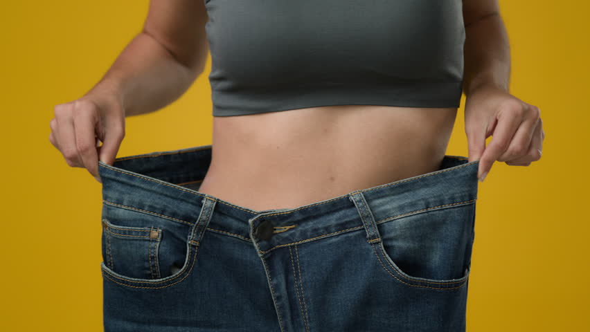 Unrecognizable sport woman in large big size jeans. Close up female strong abdominal tummy slim slender thin body waist girl showing body slimming fitness weight loss dancing happy healthy lifestyle Royalty-Free Stock Footage #1099081331