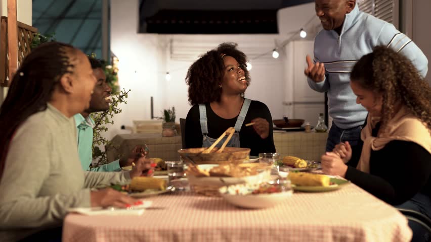 Happy african family eating dinner together at home on patio Royalty-Free Stock Footage #1099085335