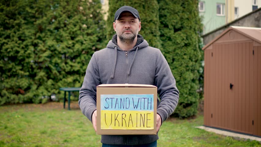 Portrait responsible woman volunteer holds cardboard box with donated food and humanitarian aids for ukrainian refugees from caring people. Help Ukraine in war with russian aggression