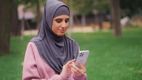 Happy arab woman in hijab having video call on smartphone, waving hand on camera