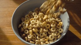 Closeup slow motion overhead shot of multi grain hoops dry cereal being poured into a breakfast bowl on a pine surface. - Powered by Shutterstock - Get 15% off with code: PIKWIZARD15