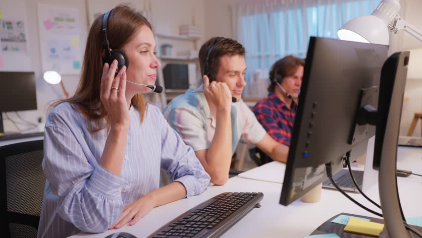 Caucasian businessman and woman call center work in office corporate. Attractive young employee worker people sit on table, wear headset and use laptop computer talk to support customer at workplace.