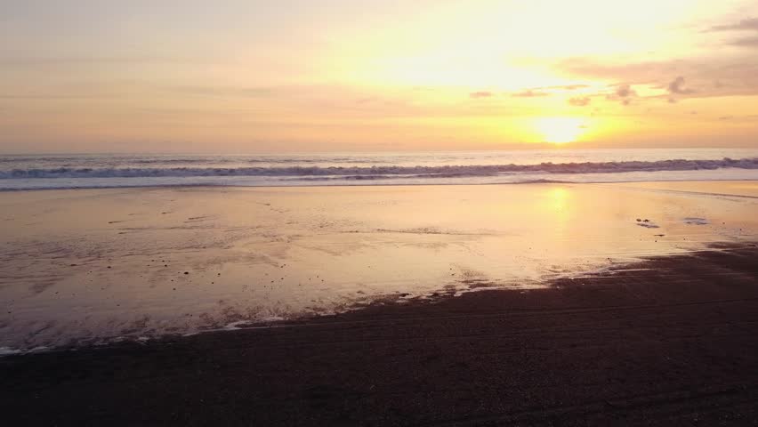 Aerial view of Bali beach island and sliver of sand on Sunset beach in the evening, sunset sea view with mountains, drone aerial.