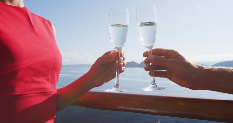 Luxury cruise ship travel couple toasting champagne glasses for celebration honeymoon. Holiday drinking doing cheers at sunset view sun flare of cruise holiday destination | Shutterstock HD Video #1099094811