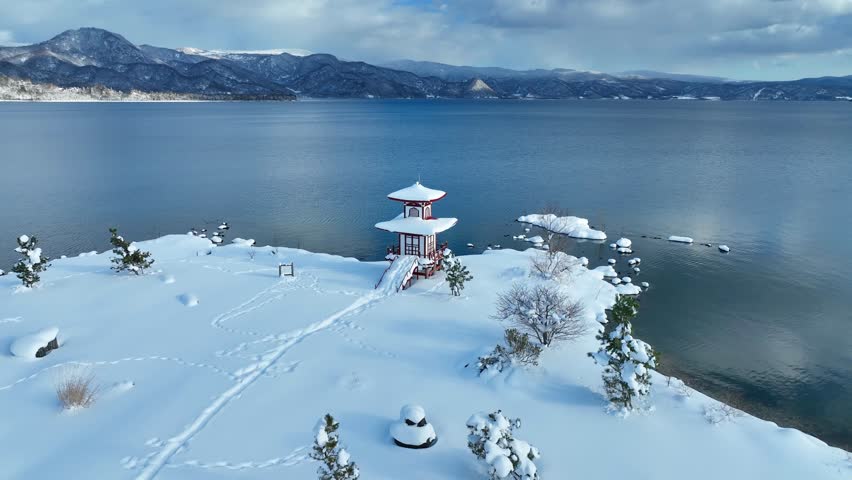 snowy lake and pagoda in Hokkaido, Japan, Asian nature in winter, aerial view of scenic mountain lake with Japanese traditional pagoda temple. High quality 4k footage Royalty-Free Stock Footage #1099098649
