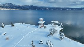snowy lake and pagoda in Hokkaido, Japan, Asian nature in winter, aerial view of scenic mountain lake with Japanese traditional pagoda temple. High quality 4k footage