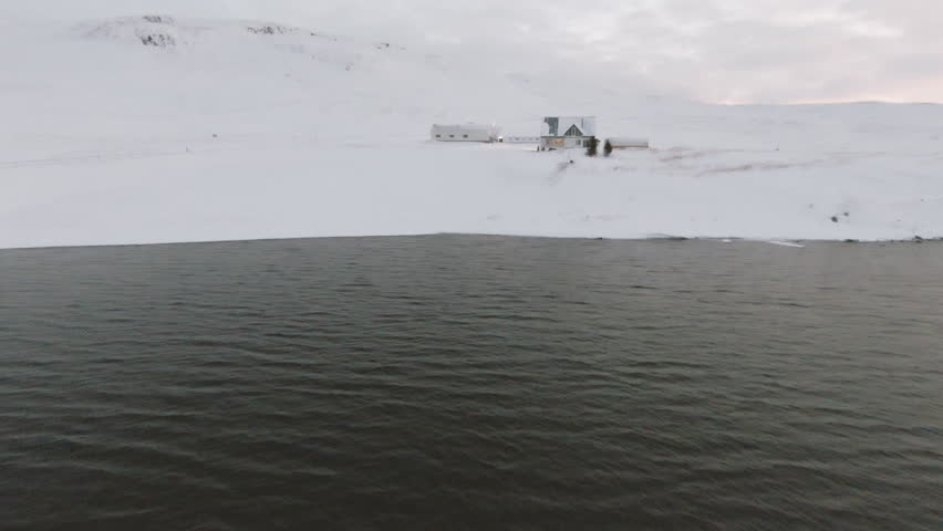 Winter mountain landscape with house on ocean shore. Dolly forward 