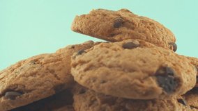 A macro close up shot of a white plate full of chocolate chip cookies, on a 360 rotating stand, studio lighting, slow motion, 4K video.