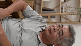 Vertical Screen: shocked old asian man sitting on sofa and answer smartphone call while hearing bad news. confused grandpa in glasses worried about his family - Powered by Shutterstock - Get 15% off with code: PIKWIZARD15