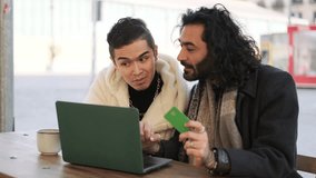 Gay couple talking while buying online using a laptop