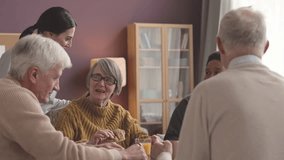 Helpful young female nurse taking care of ethnically diverse seniors sitting together at dining table having breakfast - Powered by Shutterstock - Get 15% off with code: PIKWIZARD15