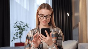 Adorable beautiful blonde female freelancer sudent wearing smart casual clothes and glasses, using smartphoneat at home, Manager Connecting with People Online, Browsing Internet, Social media.