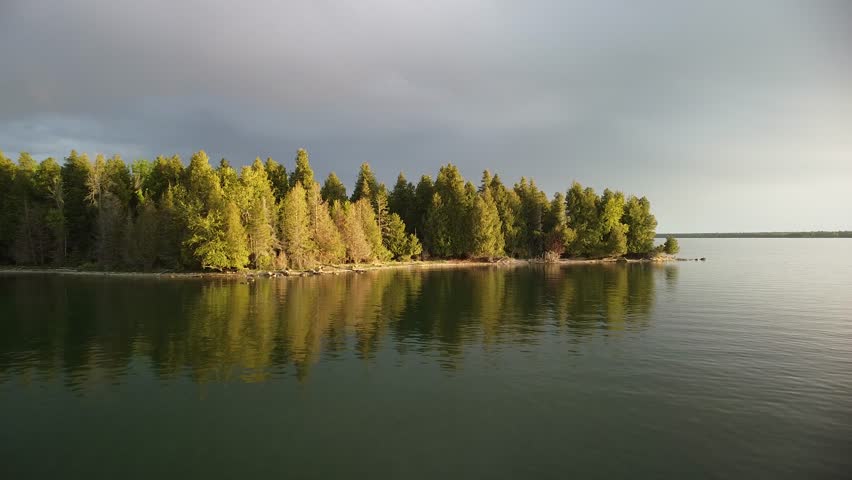 Aerial Flyover Golden Hour Forested Trees with Lake - Les Cheneaux Islands, Michigan