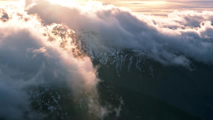 Dramatic movement of clouds over the mountains in winter.Light illuminates the clouds at sunset | Shutterstock HD Video #1099113397