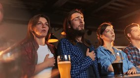 Group of young people, men and women meeting at pub to watch sport match translation. Proudly singing anthem of team. Competition, championship, match translation. Emotions. Drinking beer - Powered by Shutterstock - Get 15% off with code: PIKWIZARD15