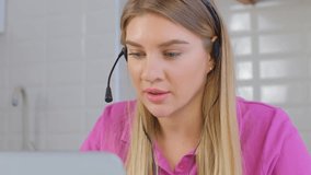 Call center operator wearing headset talks to client during a call. Friendly helpdesk speacialist speaking with customer online