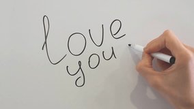 Woman draws a heart next to the love you note on the fridge and hangs a marker.