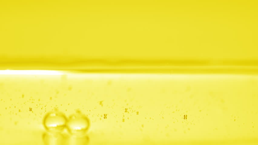 Abstract skincare cosmetics with vitamin C formulation concept | Macro shot of yellow transparent bubbles sink to the liquid surface on yellow background | Shutterstock HD Video #1099133671