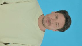 Handsome Young Man Pointing at the Camera on Blue Background, Vertical Video
