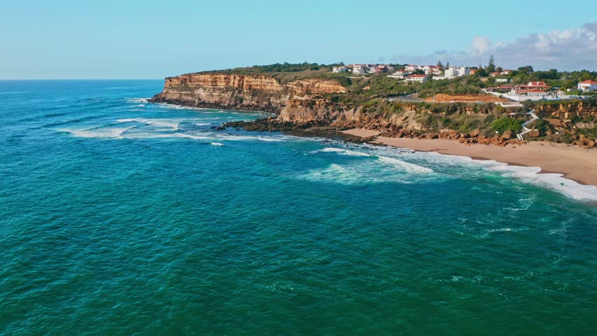 Beautiful panoramic view from drone to beautiful seacoast.  Beautiful sandy beach on a sunny summer day on the Atlantic coast in Portugal.  Touristic travel place.   Aerial slow motion footage of ocea