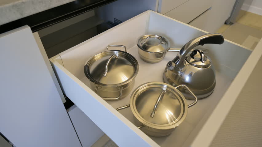 Open drawer with kitchen utensils and cookware casseroles at modern classic kitchen furnitures, tilt shot | Shutterstock HD Video #1099145031