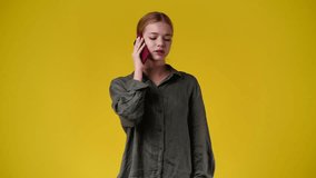4k slow motion video of one girl talking over the phone on yellow background.