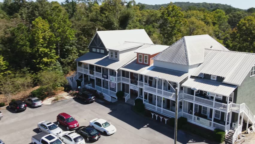 Aerial fly over of boutiques, revealing trees and water behind the charming shops at Old Town Helena, Alabama