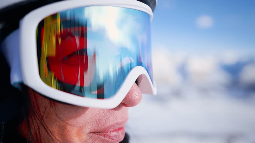 Close-up ski helmet and ski glasses with reflection mountains in snow on face young woman. Girl wear sport clothing in winter resort. Portrait beautiful female. Enjoy healthy rest, active lifestyle. Royalty-Free Stock Footage #1099156107