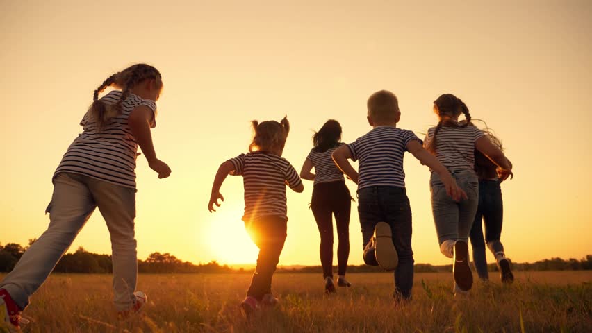 Happy family, mom, dad, son and daughters run across the field in the Park. Happy family at sunset in the rays of the sun running through a green field. teamwork. The concept of a happy family. Royalty-Free Stock Footage #1099157749