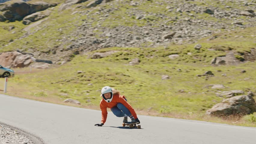 Cinematic downhill longboard session. Young woman skateboarding and making tricks between the curves on a mountain pass. Concept about extreme sports and people	