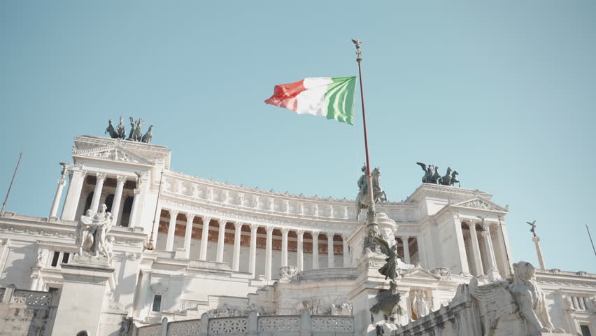 White stone historical monument to Vittorio Emanuele II in Rome on Venice Square, architectural monument of ancient Roman Empire, Italian flag waving on the sides of famous building. High quality 4k