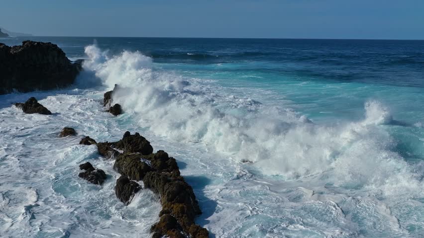 Slow motion aerial shot of ocean wave breaks on the coastal rocks forming white foam and splashes. Flying over atlantic ocean coastline. Nature wonders Royalty-Free Stock Footage #1099165573