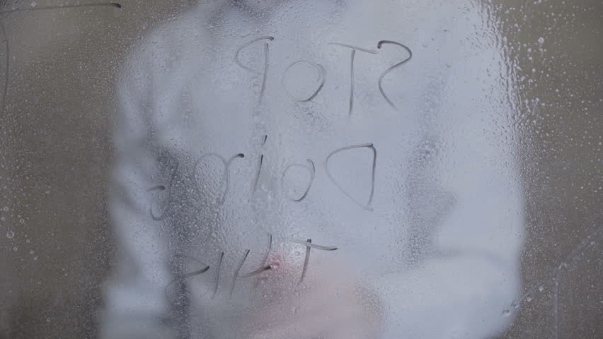 young man cleans windows with spray at home
