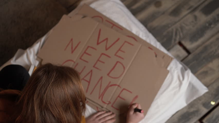 a girl activist in a college dormitory sits on a bed at night and writes a poster with a red marker we need change. The concept of preparing for a protest action. Royalty-Free Stock Footage #1099166795