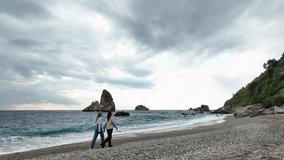 Two young beautiful women walking along beach, along sea or ocean. aerial view 4K - Powered by Shutterstock - Get 15% off with code: PIKWIZARD15