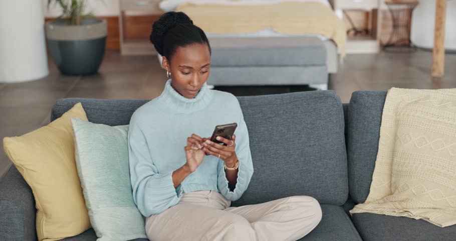 Black woman, phone and online shopping on sofa in home for clothes or pants. Ecommerce, delivery and girl on 5g mobile shopping on internet store, shop or web app for fashion sales or discount deal. | Shutterstock HD Video #1099172393
