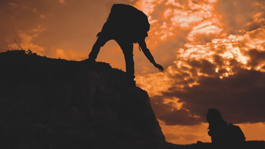 teamwork help business travel silhouette at sunset sunlight slow motion video concept. man and girl holds out a helping hand mutual assistance camping adventure a pair of hikers climb a mountain Royalty-Free Stock Footage #1099173407