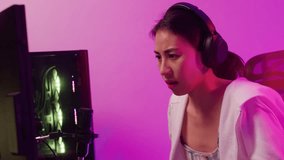 Young Asia female online video game addict sit on gaming chair wear headset serious face pc computer screen upset lose competition tournament championship at house. Gamer girl shouting scream angry.
