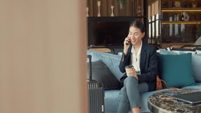 Youth Asia female passenger wear suit sit on couch with phone call speak discuss talk work in airline lounge drink tea wait for transit international airport. Hotel Travel business trip concept. - Powered by Shutterstock - Get 15% off with code: PIKWIZARD15