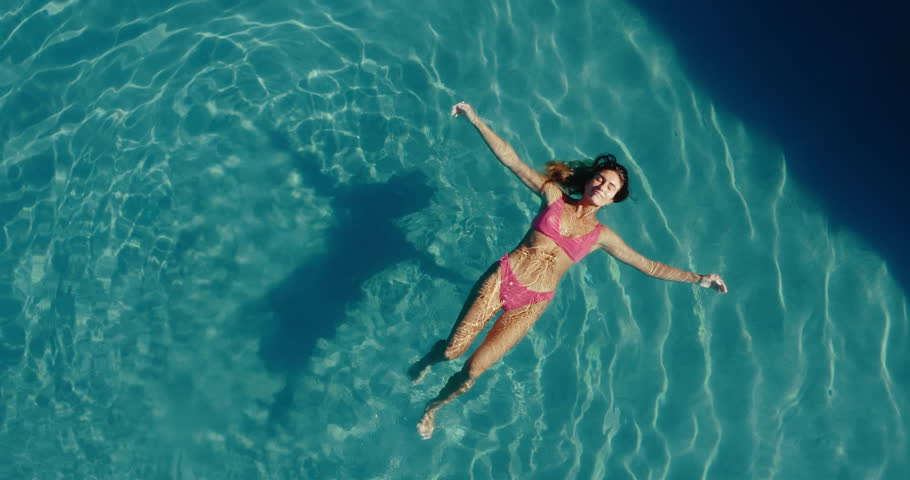 Aerial view of beautiful woman floating and relaxing in the the pool at luxury resort spa | Shutterstock HD Video #1099180715