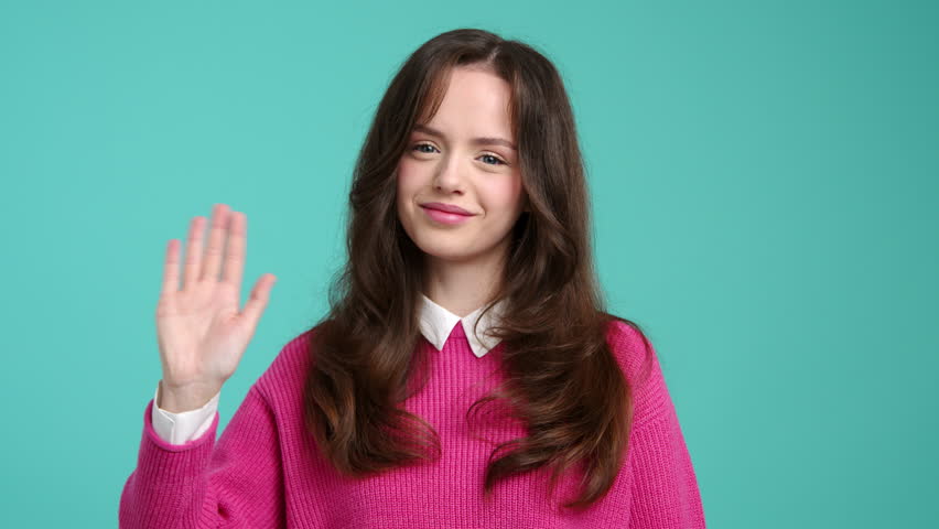 Portrait of caucasian, brunette-haired teenager greeting someone. Close-up view of a cheerful girl waving her hand. High quality 4k footage | Shutterstock HD Video #1099182849