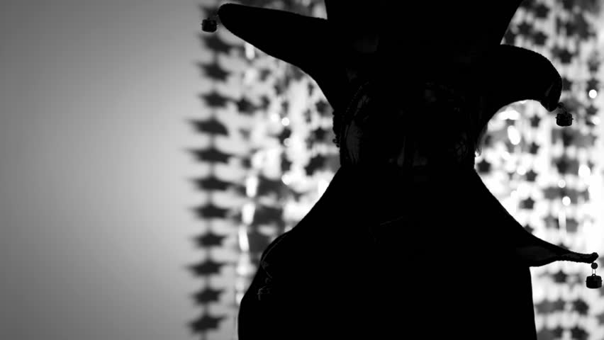 Person in the carnival mask of harlequin in the darkness.
